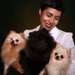 Happy woman holding three adorable Pomeranian dogs, radiating joy and warmth.