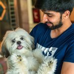 Happy man holding a playful Shih Tzu dog indoors. Perfect for pet lovers and companionship themes.